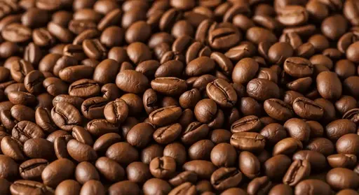 A close-up, full-frame background of a large, dense pile of medium-dark roasted whole coffee beans.